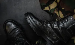 Czarne buty wojskowe i fragment munduru maskującego. Zastanawiasz się, jak napisać wniosek o zwolnienie z zawodowej służby wojskowej?