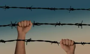 Dłonie trzymające drut kolczasty na tle nieba.