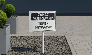Znak "Zakaz parkowania, teren prywatny" na drodze wewnętrznej. Obok ozdobne krzewy w donicach.