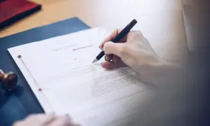 Dłoń pisze piórem na dokumencie testamentu. To ważny testament allograficzny, który określa przyszłość.