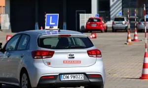 Srebrny samochód z literą "L" na dachu, gotowy do egzaminu na prawo jazdy A1.