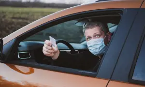 Mężczyzna w masce pokazuje numer blankietu prawa jazdy.