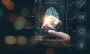 Dłoń skanuje odcisk palca na ekranie, symbolizując dostęp i bezpieczeństwo. System chroni przed atakami typu ddos.