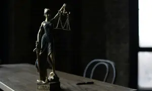 Figurka Temidy z wagą i mieczem na drewnianym stole.