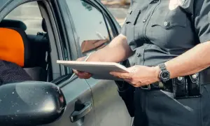 Policjant spisuje dane podczas kontroli drogowej. Widoczna rejestracja kk.