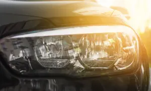 Refleksy na reflektorach samochodu, gdzie światła mijania i dzienne tworzą razem odbicie otoczenia.