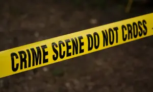 Żółta taśma z napisem "CRIME SCENE DO NOT CROSS" na ciemnym tle.