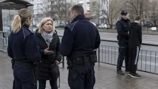 Policjanci przesłuchują kobietę, która zgłosiła rozbój. W tle stoi drugi funkcjonariusz z zatrzymanym młodzieńcem.