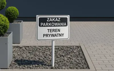 Znak "Zakaz parkowania, teren prywatny" na drodze wewnętrznej. Obok ozdobne krzewy w donicach.