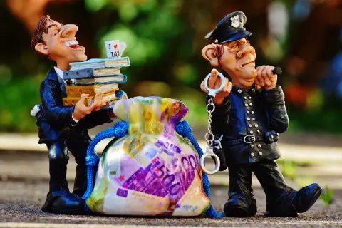 Figurki policjanta z kajdankami i mężczyzny z książkami i torbą pieniędzy.