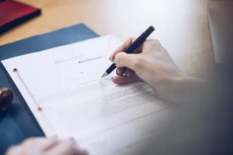 Dłoń pisze piórem na dokumencie testamentu. To ważny testament allograficzny, który określa przyszłość.