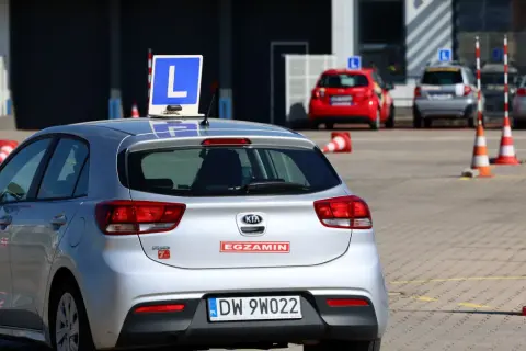 Srebrny samochód z literą "L" na dachu, gotowy do egzaminu na prawo jazdy A1.