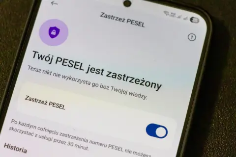 Ekran telefonu z informacją "Twój PESEL jest zastrzeżony" i ikoną tarczy z kłódką.