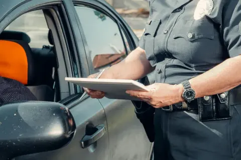 Policjant spisuje dane podczas kontroli drogowej. Widoczna rejestracja kk.