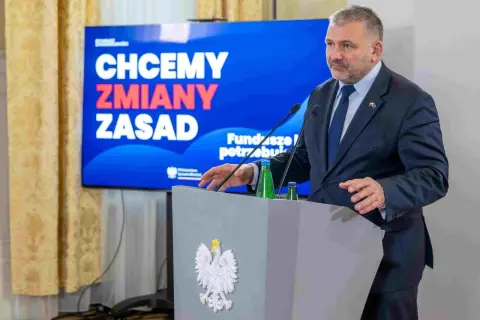 Mężczyzna w garniturze przemawia przy mównicy z godłem Polski. Na ekranie za nim napis: "Chcemy zmiany zasad". Mowa dotyczy funduszu sprawiedliwości.