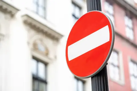 Znak B-18 "zakaz wjazdu" na słupku. Uważaj, bo za ignorowanie tego znaku grozi mandat.