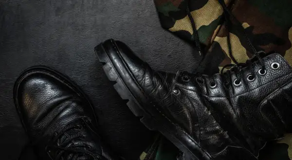 Czarne buty wojskowe i fragment munduru maskującego. Zastanawiasz się, jak napisać wniosek o zwolnienie z zawodowej służby wojskowej?
