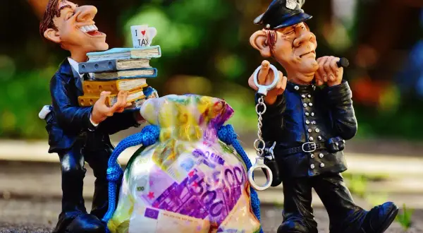 Figurki policjanta z kajdankami i mężczyzny z książkami i torbą pieniędzy.
