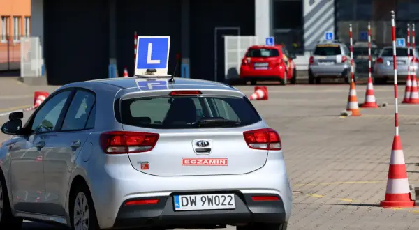Srebrny samochód z literą "L" na dachu, gotowy do egzaminu na prawo jazdy A1.
