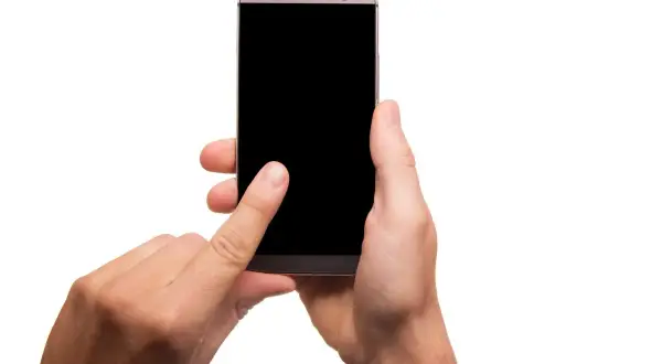 Dłoń trzymająca smartfon z czarnym ekranem, palec wskazujący dotyka ekranu.
