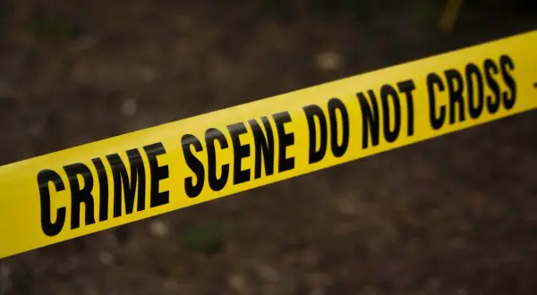 Żółta taśma z napisem "CRIME SCENE DO NOT CROSS" na ciemnym tle.