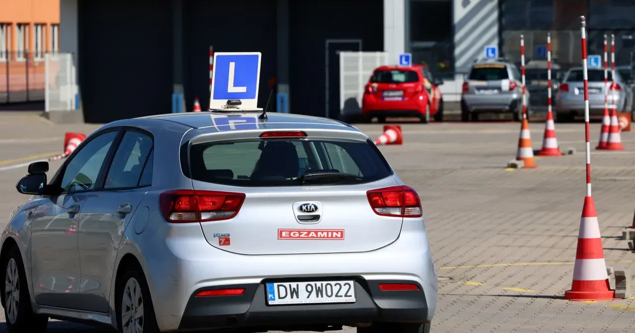Srebrny samochód z literą "L" na dachu, gotowy do egzaminu na prawo jazdy A1.