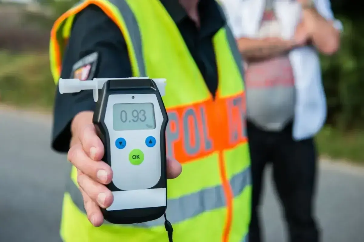 Policjant pokazuje alkomat z wynikiem 0.93. To przypomnienie o **limicie alkoholu w Polsce** i odpowiedzialności za kierowanie po spożyciu.