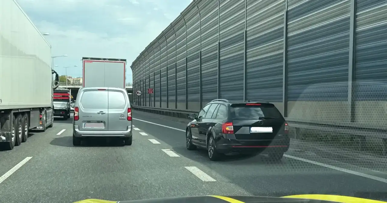 Samochody stoją w korku na autostradzie. Kierowcy czekają na możliwość zjazdu, a jazda na suwak jest jedynym rozwiązaniem.