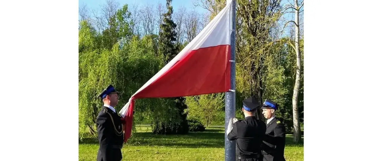 Poczet sztandarowy w galowych mundurach podnosi polską flagę na maszcie.
