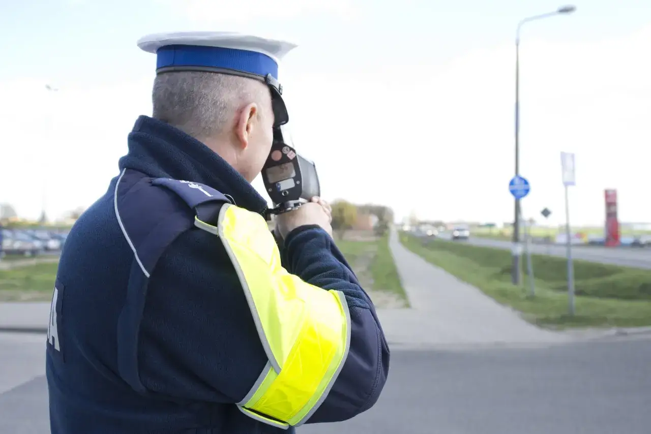 Policjant mierzy prędkość pojazdów. Może to być część jego pracy, która wymaga ukończenia kursu reedukacyjnego.