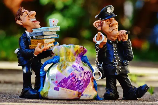 Figurki policjanta z kajdankami i mężczyzny z książkami i torbą pieniędzy.
