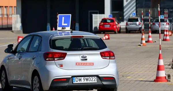 Srebrny samochód z literą "L" na dachu, gotowy do egzaminu na prawo jazdy A1.
