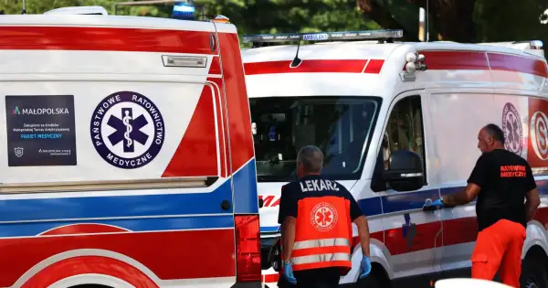 Dwie karetki pogotowia, ratownicy medyczni w kamizelkach odblaskowych.