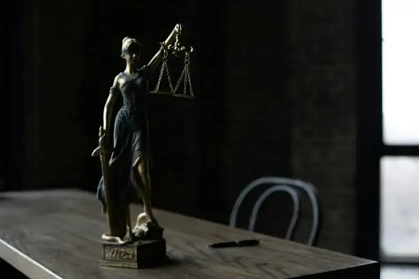Figurka Temidy z wagą i mieczem na drewnianym stole.