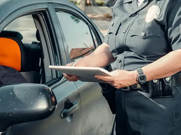Policjant spisuje dane podczas kontroli drogowej. Widoczna rejestracja kk.