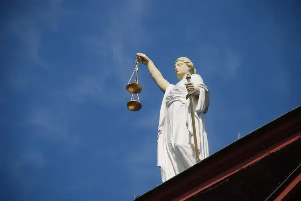 Posąg Temidy z wagą i mieczem na tle błękitnego nieba. Symbol sprawiedliwości, 4cmc.