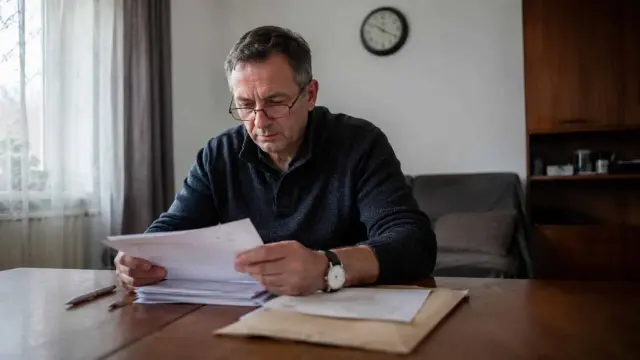 Mężczyzna w okularach przegląda dokumenty, być może analizując potencjalne wykroczenie.