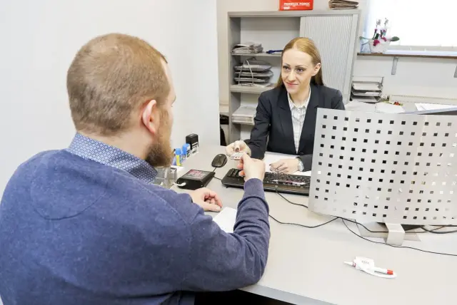 Mężczyzna przekazuje dokumenty do wymiany prawa jazdy urzędniczce.